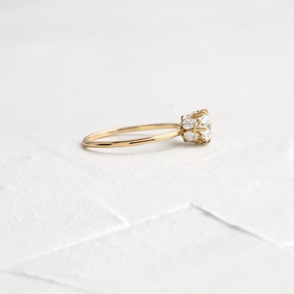 Round cut lab grown diamond with accent pear cut hidden halo engagement ring crafted in 14k yellow gold.