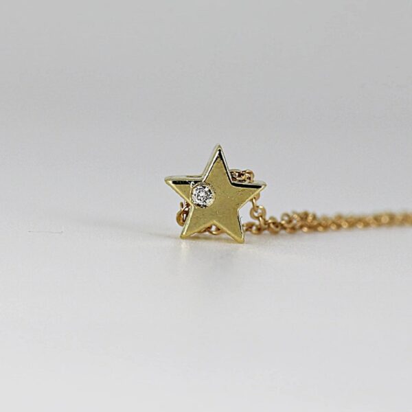 Unique star shaped round cut lab grown diamond on side of pendant is crafted in 14k yellow gold.