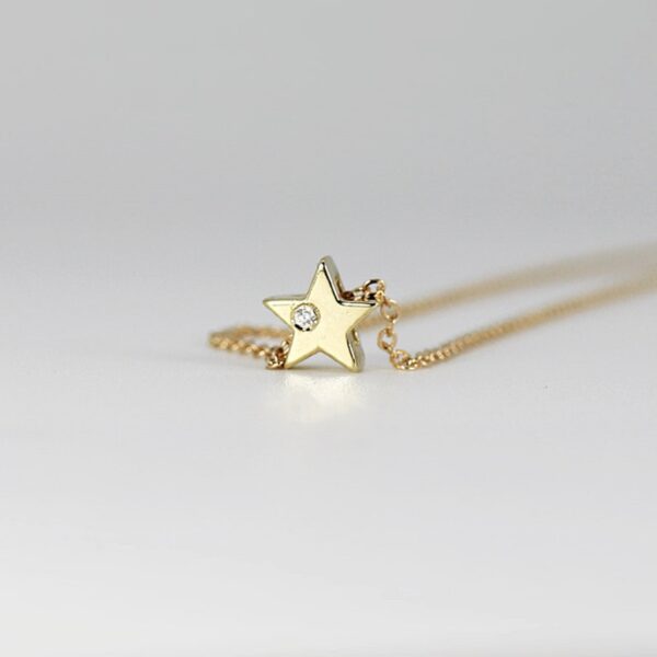 Unique star shaped round cut lab grown diamond on side of pendant is crafted in 14k yellow gold.