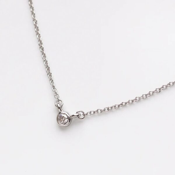 Tiny bezel set round cut lab grown diamond charm pendant is crafted in 14k white gold.